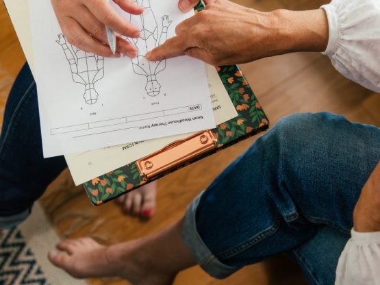 A client showing Sarah Woodhouse her current health and wellbeing issues on a diagram of the human body.