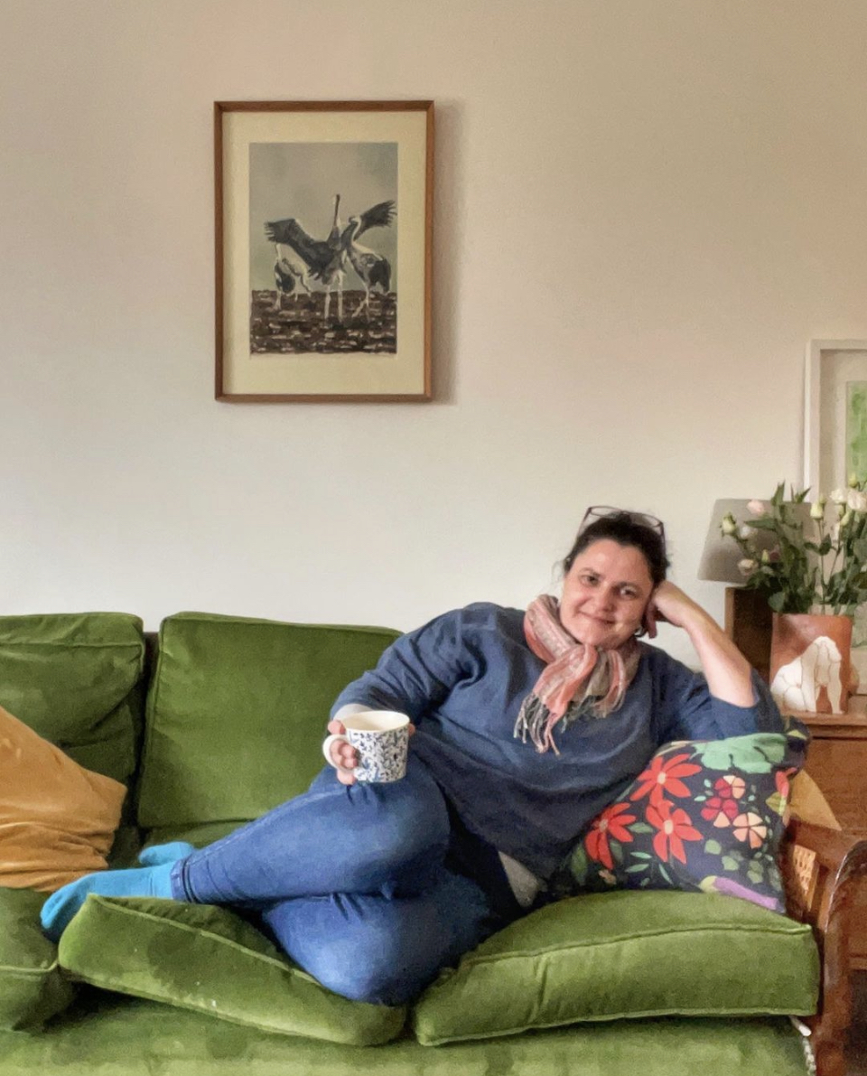 About Me: Sarah Woodhouse Therapy relaxing at home on her green sofa with a coffee in her hand