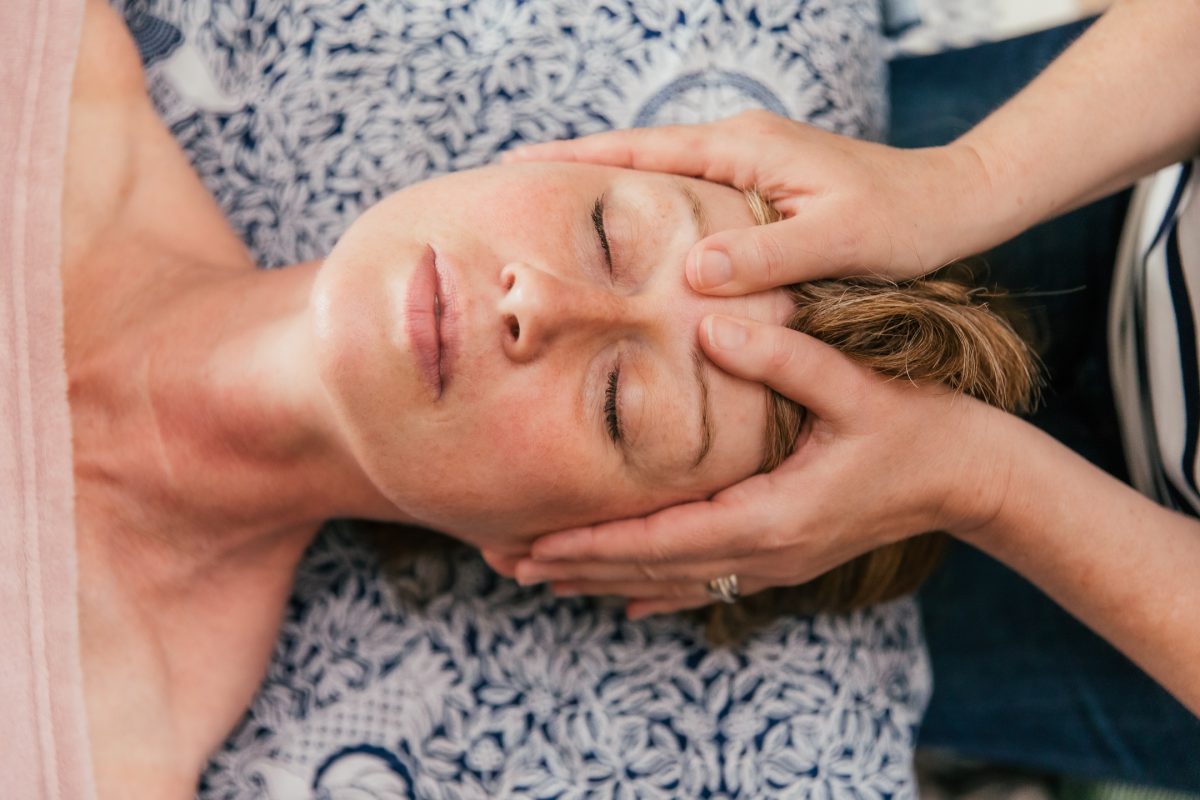 A close up of the clients face with Sarah working on key acupressure and sinus release points on the edge of the clients eyebrows.