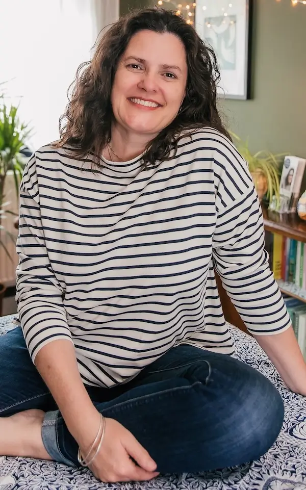 Sarah Woodhouse, holistic therapist, smiling warmly in her treatment room.