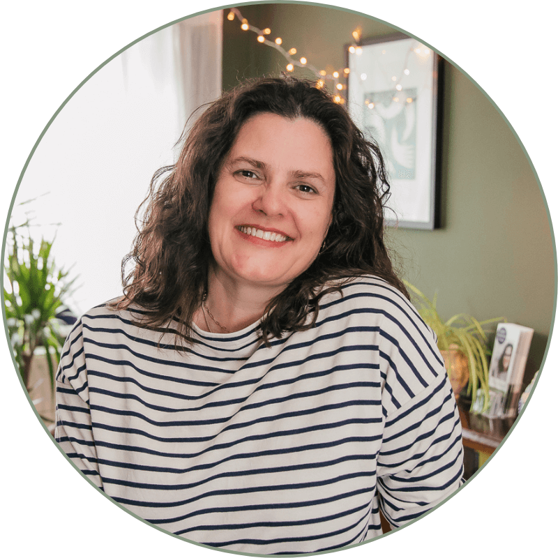 Sarah Woodhouse, holistic therapist, smiling warmly in her treatment room.